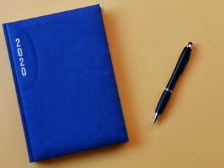 Notebook with pen on yellow background. 