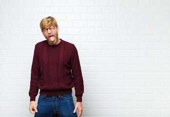 young blonde man with cheerful, carefree, rebellious attitude, joking and sticking tongue out,...