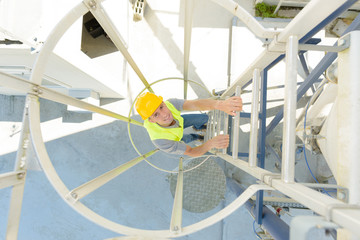 man climbs up an vertical ladder factory