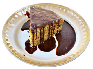 Sponge cake with chocolate icing on a plate isolated