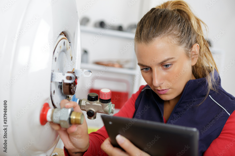 Wall mural female technician servicing a boiler using tablet computer