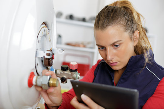 female technician servicing a boiler using tablet computer