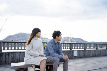 ベンチに座り楽しそうに会話をする若いカップル Wall Mural West Photo