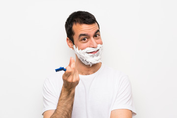 Man shaving his beard over isolated white background making money gesture
