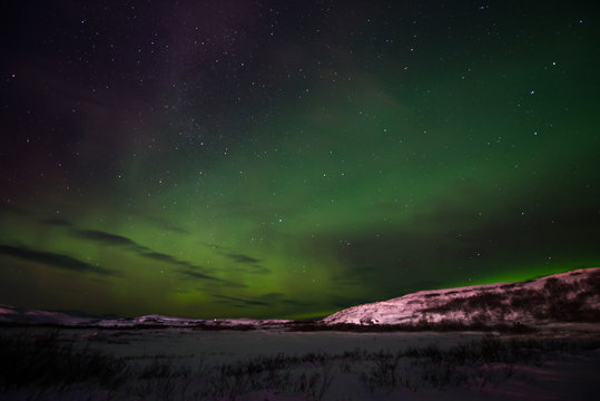 hills, clear starry sky and colorful Northern lights, an incredible natural phenomenon