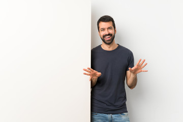 Young handsome man with beard holding a big empty placard smiling