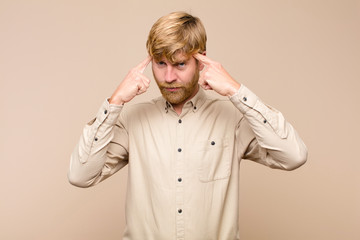 young blonde man with a serious and concentrated look, brainstorming and thinking about a challenging problem against flat wall