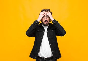 young crazy handsome man feeling horrified and shocked, raising hands to head and panicking at a...