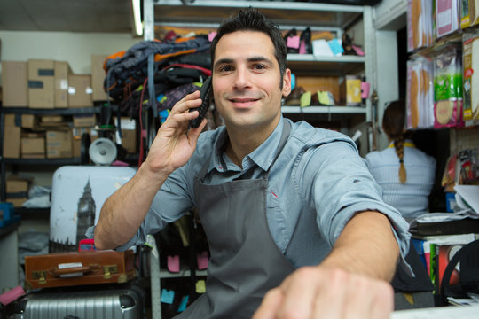 shoemaker talking on mobile phone in workshop