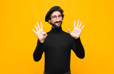 young french artist man smiling and looking friendly, showing number nine or ninth with hand...