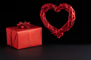 Valentine day concept. Wicker levitating red heart and gift boxes on black background. Greeeting card, postcard