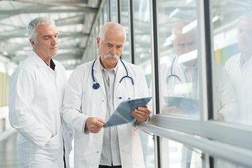 two senior male doctors looking at clipboard