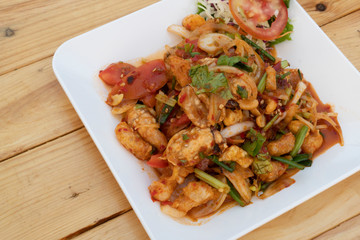 Stir fried three flavors in a white dish placed on a wooden floor.