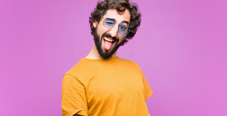young crazy cool man with cheerful, carefree, rebellious attitude, joking and sticking tongue out,...