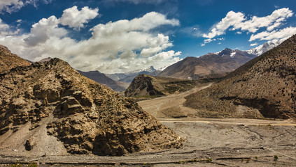 A dramatic landscape with the arid, rocky hills of Mustang and the valley surrounding the village of Marpha under blue skies on the Annapurna Circuit trekking trail in the Nepal Himalaya. 