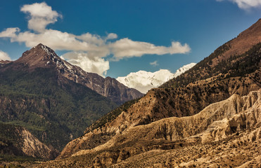 The rugged hilly landscape of the high, snow covered mountains on the Annapurna Circuit trekking trail in the Nepal Himalaya.