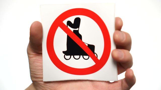 No roller skating allowed sign isolated. Male hand holding no roller skating sign