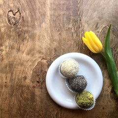 Yellow tulip and candies on a wooden background with copy space, top view. Holiday morning concept.
