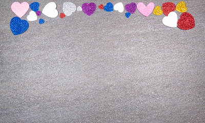 colorful hearts of glitter of all colors on a gray granite background. Concept of valentines day and love in general