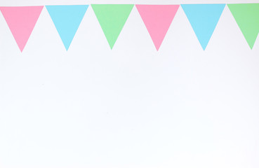 Colorful garland of paper triangles on a white background. Greeting card. Flat lay style. Copyspace for text.