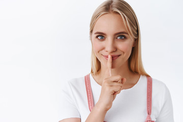Sly and sassy attractive feminine blond woman with blue eyes, smiling secretly telling you rumors,...