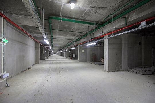 Underground parking in construction phase. Empty garage in basement of office building under construction. Parking without cars. Reinforced concrete monolithic walls in basement of house before repair