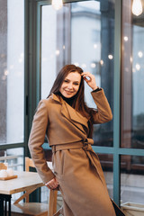 Outdoor fashion portrait of stylish young woman having fun, emotional face , laughing, Urban city street style wearing dark casual trousers, white sweater,creamy coat. and sunglasses Fashion concept.