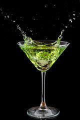 martini glass and splash from falling ice on a black background