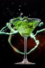 ice falls on a martini glass on a black background and lines of fire in the dark