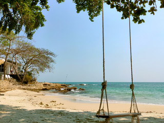 Wooden swings on the beach and peaceful sea landscape during the holidays.