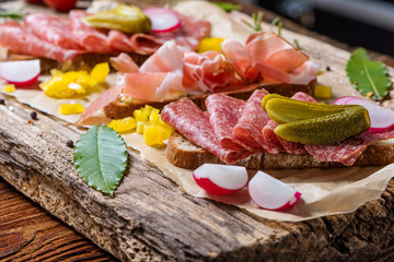 Rustic country-style buffet with ham, bacon and sausage sandwiches garnished with vegetables and...