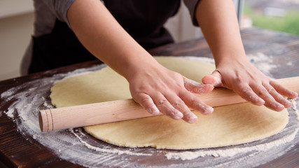 Obraz na płótnie Canvas Close up of woman rolling dough with rolling pin