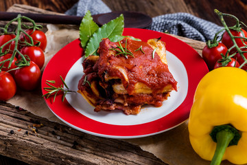Close-up of a fresh homemade lasagna made from pasta with herbs and vegetables served on a rustic rustic wooden plate