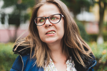 Girl with eyeglasses chewing gum outside