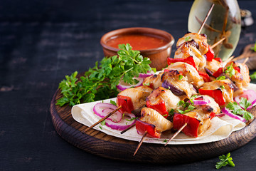 Grilled chicken kebab with paprika on a wooden board.  Grilled meat skewers, shish kebab on dark background.