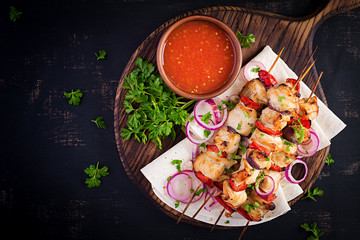 Grilled chicken kebab with paprika on a wooden board.  Grilled meat skewers, shish kebab on dark background. Top view, overhead, flat lay