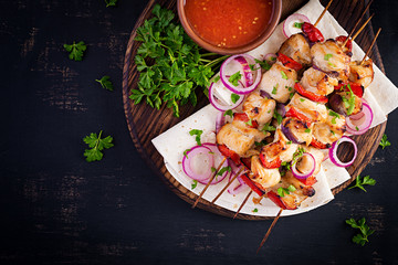 Grilled chicken kebab with paprika on a wooden board.  Grilled meat skewers, shish kebab on dark background. Top view, overhead, flat lay