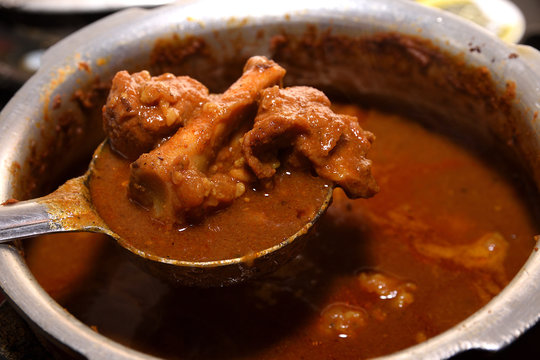 Preparation of Indian spicy Mutton curry with spoon