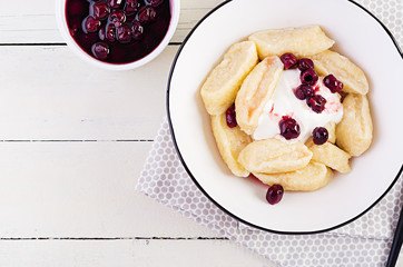 Traditional  ukrainian / russian cottage cheese lazy dumplings served with sour cream and cherry jam on white wooden background. Top view, overhead, copy space