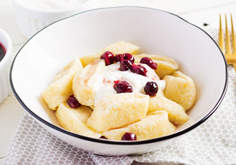 Traditional  ukrainian / russian cottage cheese lazy dumplings served with sour cream and cherry jam on white wooden background.