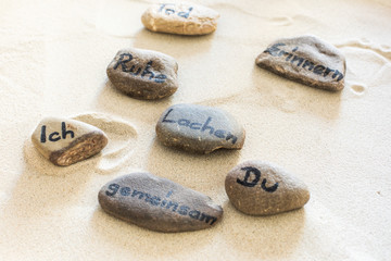 Steine mit Aufschrift liegen im Sand