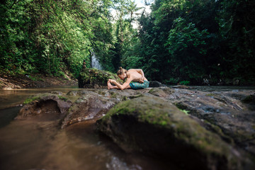 Yoga practice and meditation in nature. Man practicing near river