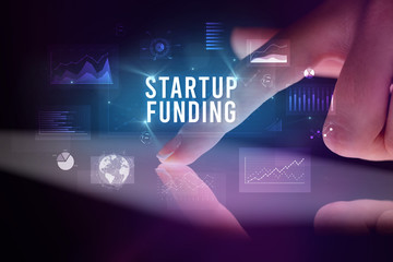 Finger touching tablet with charts and STARTUP FUNDING inscription, business concept