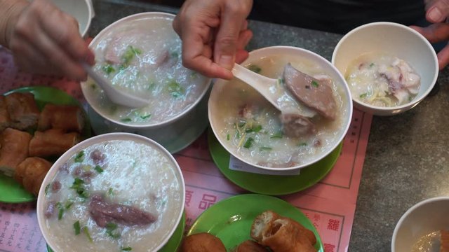 Hands eating congee boil rice and fried dough Hong Kong Cantonese style breakfast top view