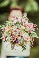 natural wedding bouquet with bride in blurry background 1