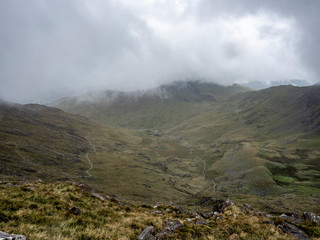 Hiking trail on the Snowdonia mountain in Wales with fog between the peaks