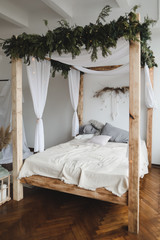 Modern home interior design. Bed with wooden canopy and pillows, blanket. Bedroom interior, scandinavian style. Home decor. 