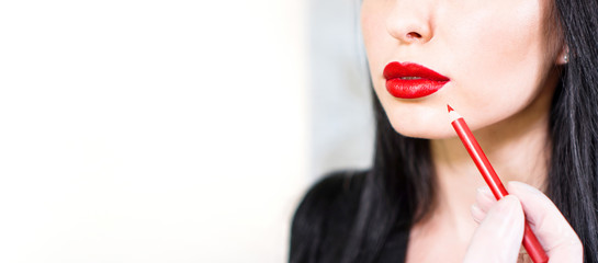 Make up banner with copy space. Makeup artist paints lips of model in red with lipstick. Beautiful...