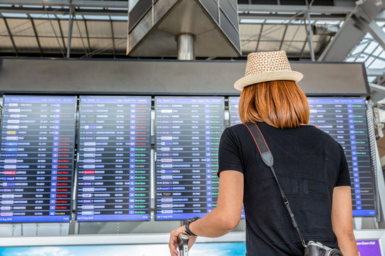 Woman standing and looking time board for flight schedule