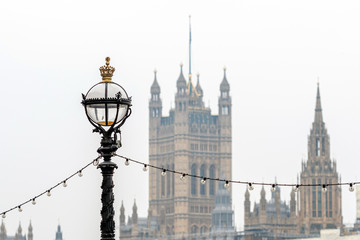 Fototapeta na wymiar Dolphin lamp standard on Thames Embankment in London at the Westminster Bridge, bloored Westminster Abbey on background